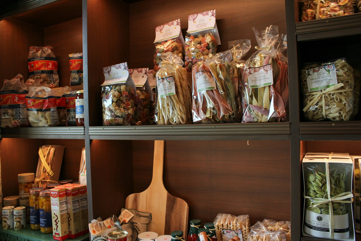 Pasta artigianale e salse esposte su una mensola di legno.